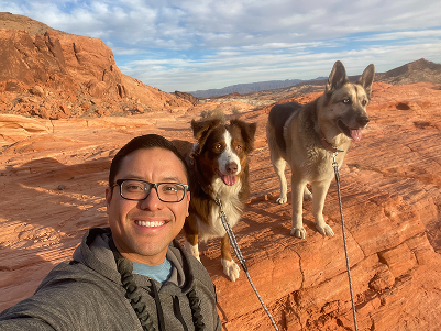 A Milunova founder hiking on red desert rocks with two foster dogs
